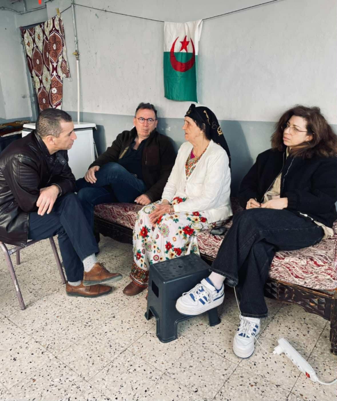 صافية كساس وفابريس ريسبوتي، برفقة سمير موترفي (جالس على كرسي)، عضو لجنة قرية آيت سولة، أجروا العديد من المقابلات مع الشهود المباشرين وغير المباشرين على مجزرة 23 ماي 1956، من بينهم السيدة ح. وبالرغم من أنها لم تكن موجودة بالقرية يوم المجزرة، إلا أنها فقدت زوجها وأبنائها، والتي تروي تجربتها ومعاناتها. (الصورة مقدمة من طرف صافية كساس).